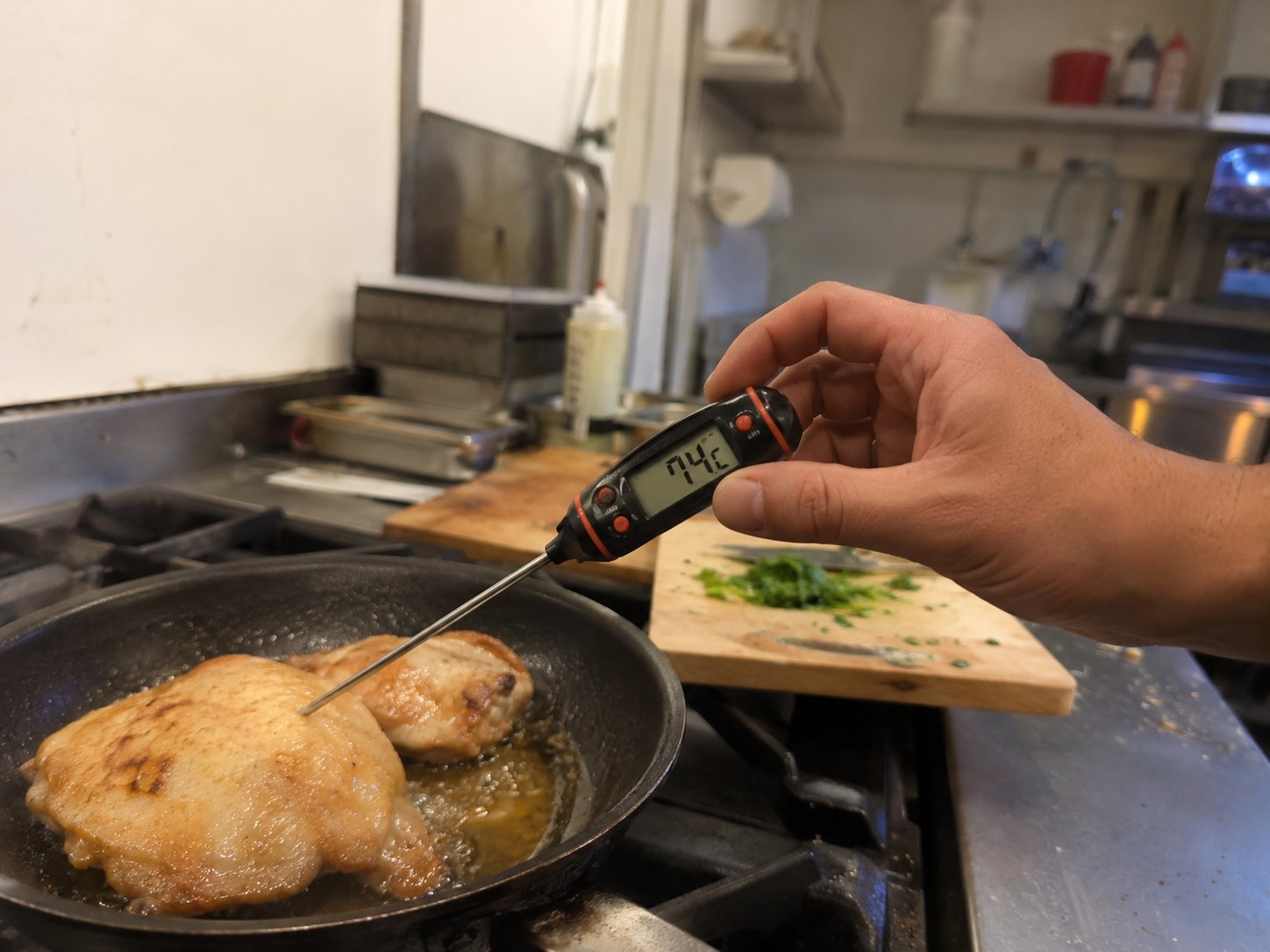 Kok meet kerntemperatuur van kip in een horecakeuken met een digitale thermometer die 74°C aangeeft